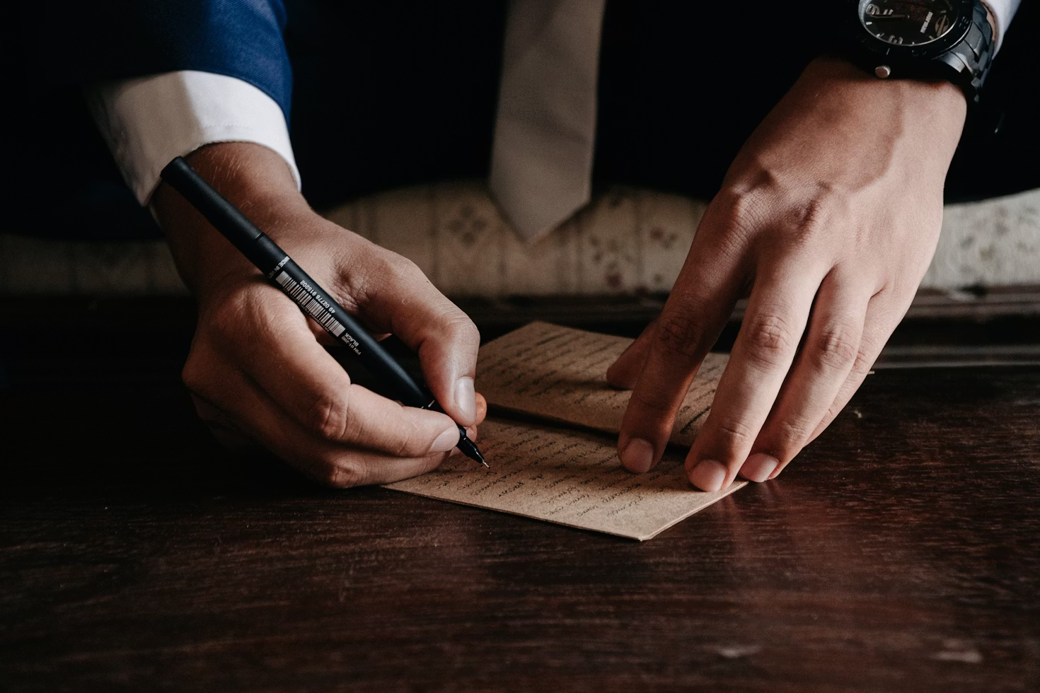 Person signing legal documents on a wooden desk with pen and paperwork